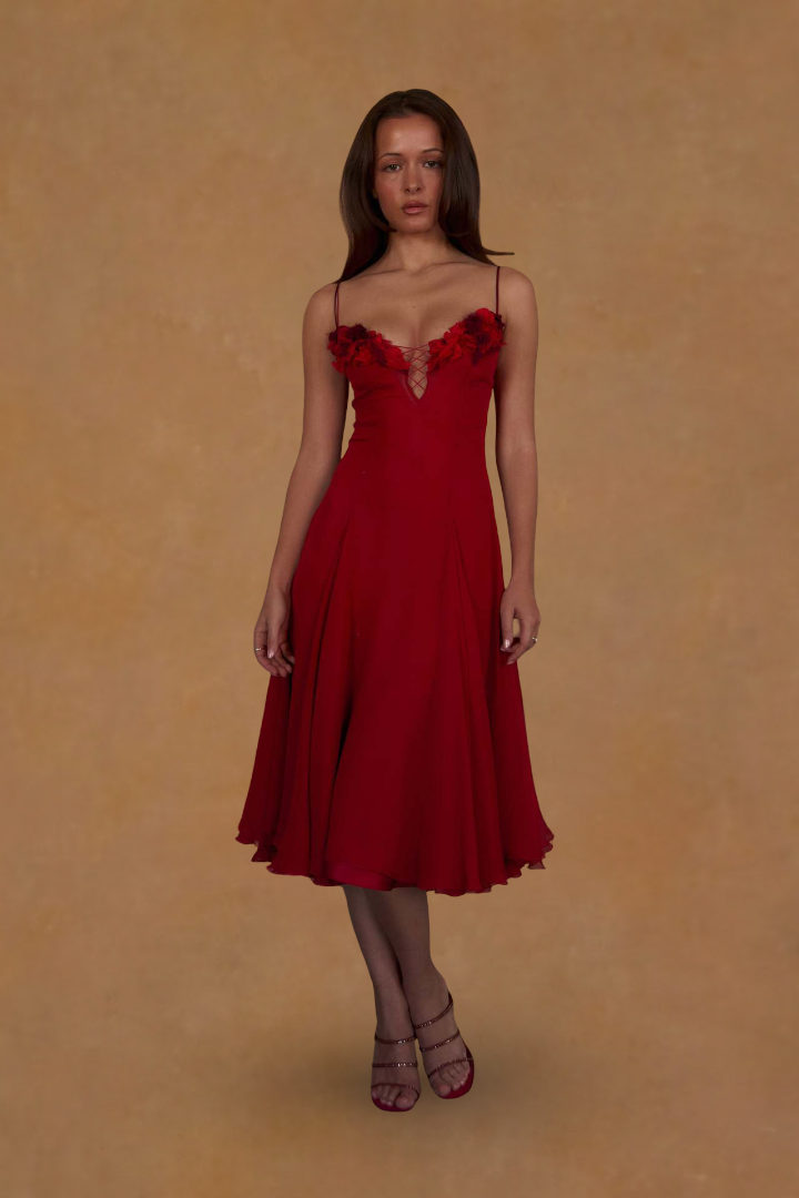 Woman wearing a red dress with floral details on a beige background