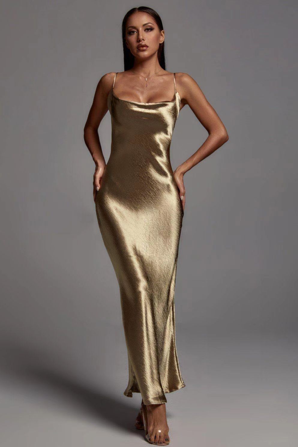 Woman wearing a gold satin dress against a gray background