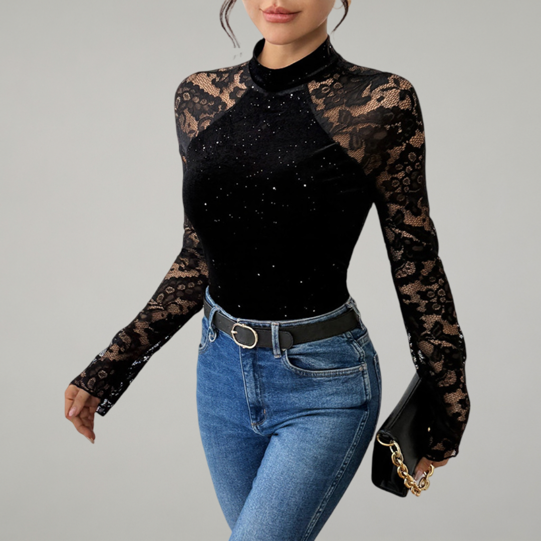 Woman wearing a black long-sleeve top with lace details and blue jeans on a gray background
