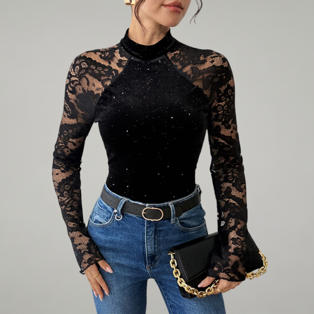 Woman wearing a black long-sleeve top with lace sleeves and jeans, holding a black clutch.