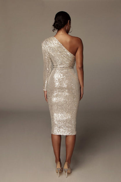 Woman wearing a silver sequin one-shoulder dress against a plain background