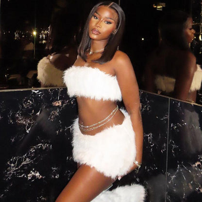 Woman in a white feathered outfit  tube top and mini skirt posing in a reflective surface setting