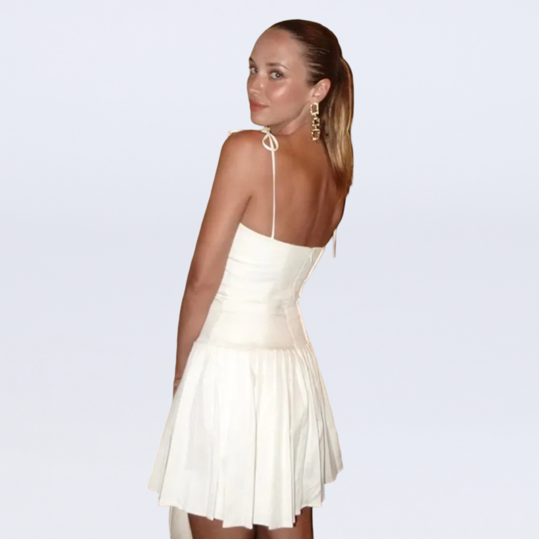 Woman wearing a white dress with thin straps on a light gray background