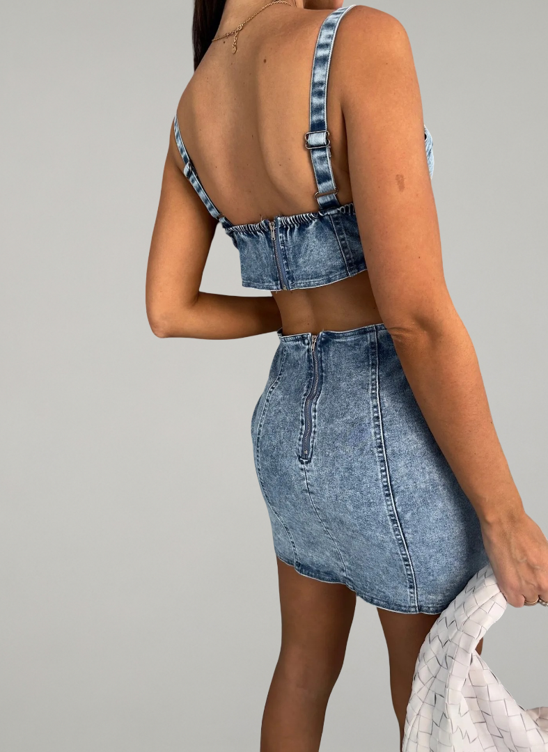 Woman wearing a denim dress with cut-out design on a gray background