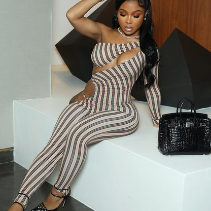 A woman wearing a striped slim-fit jumpsuit with hollow-out details. The jumpsuit is primarily monochrome with a bold striped pattern.