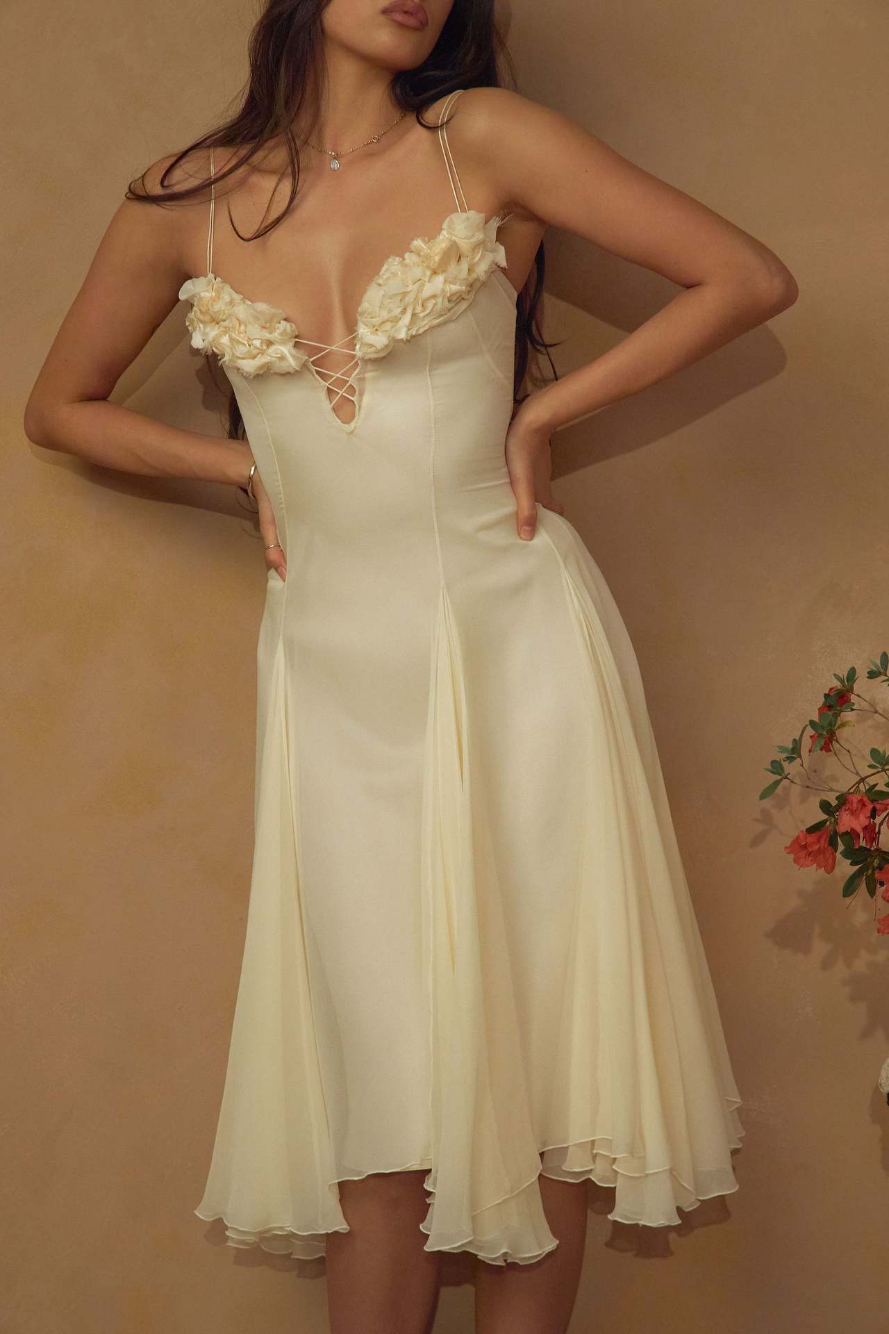 Woman wearing a white dress with floral details against a beige background