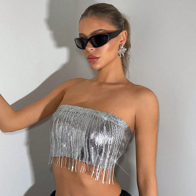Woman wearing a silver fringe top and sunglasses against a plain background