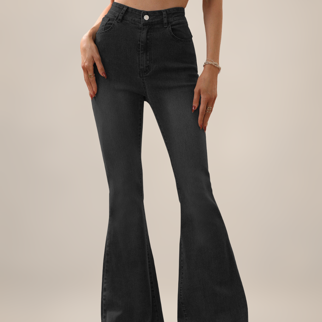 Black flared jeans worn by a person on a beige background