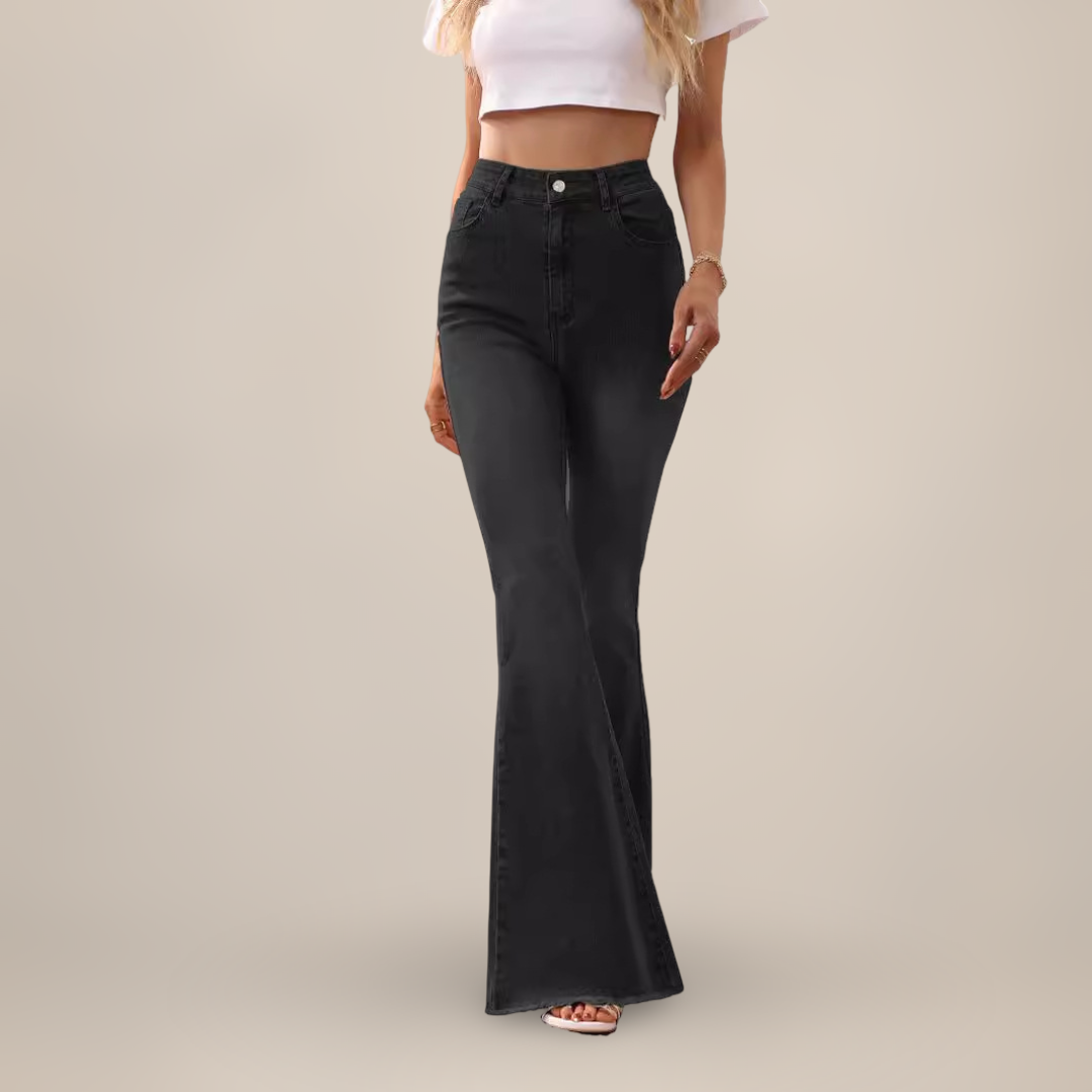 Person wearing black flared jeans on a plain background