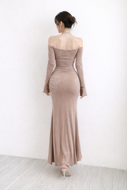 Woman wearing a long, off-shoulder dress with long sleeves against a white background