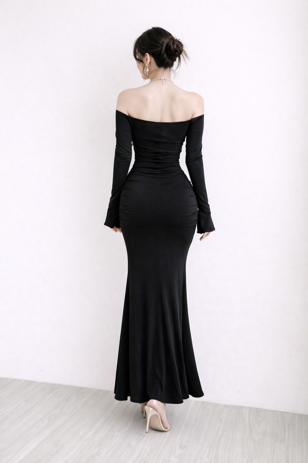 Woman wearing a black off-shoulder gown against a white background
