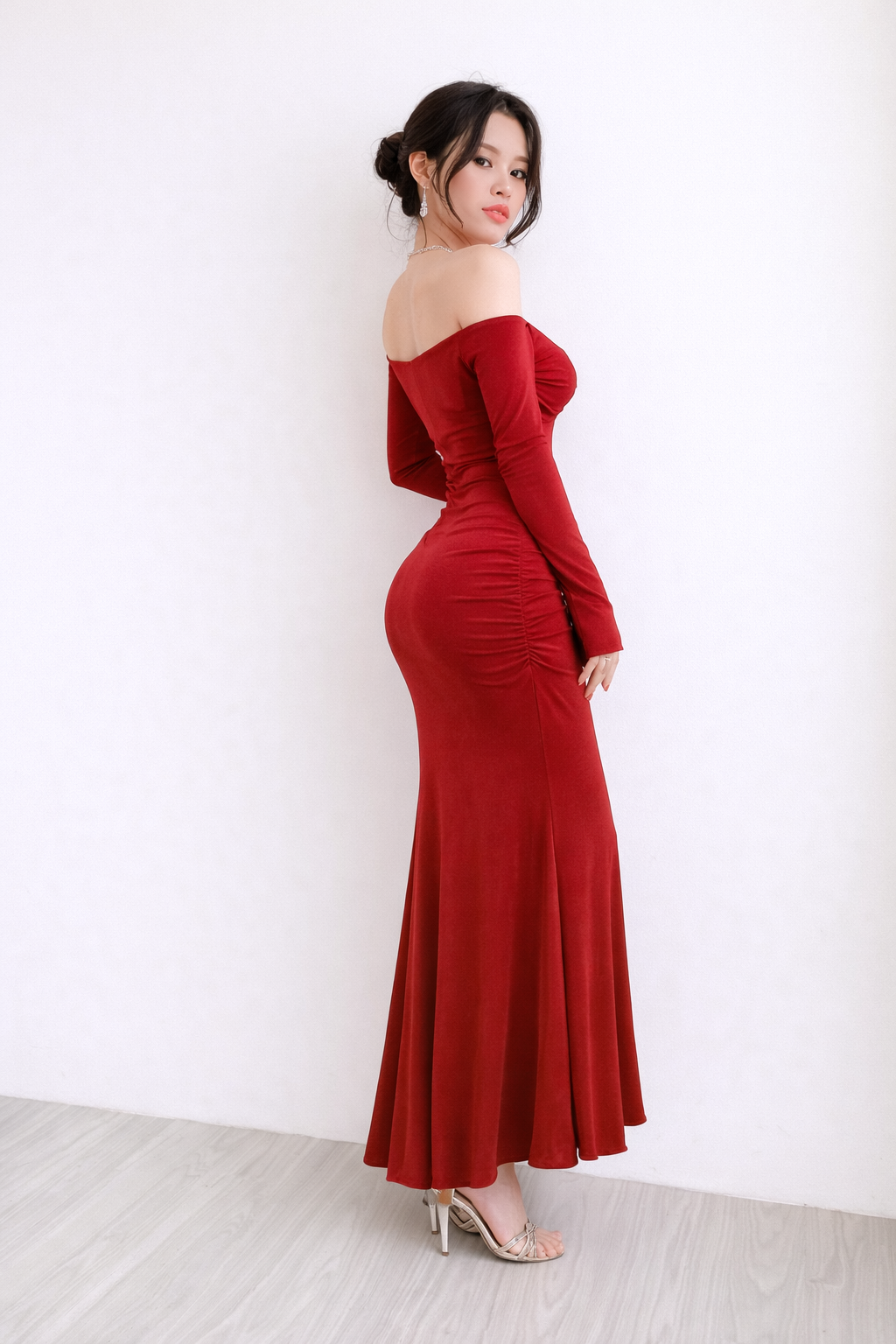 Woman wearing a red off-shoulder gown against a white background