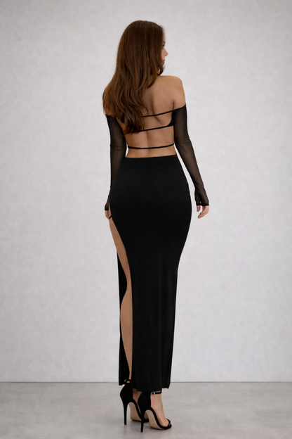 Woman wearing a black evening gown with mesh sleeves against a white background