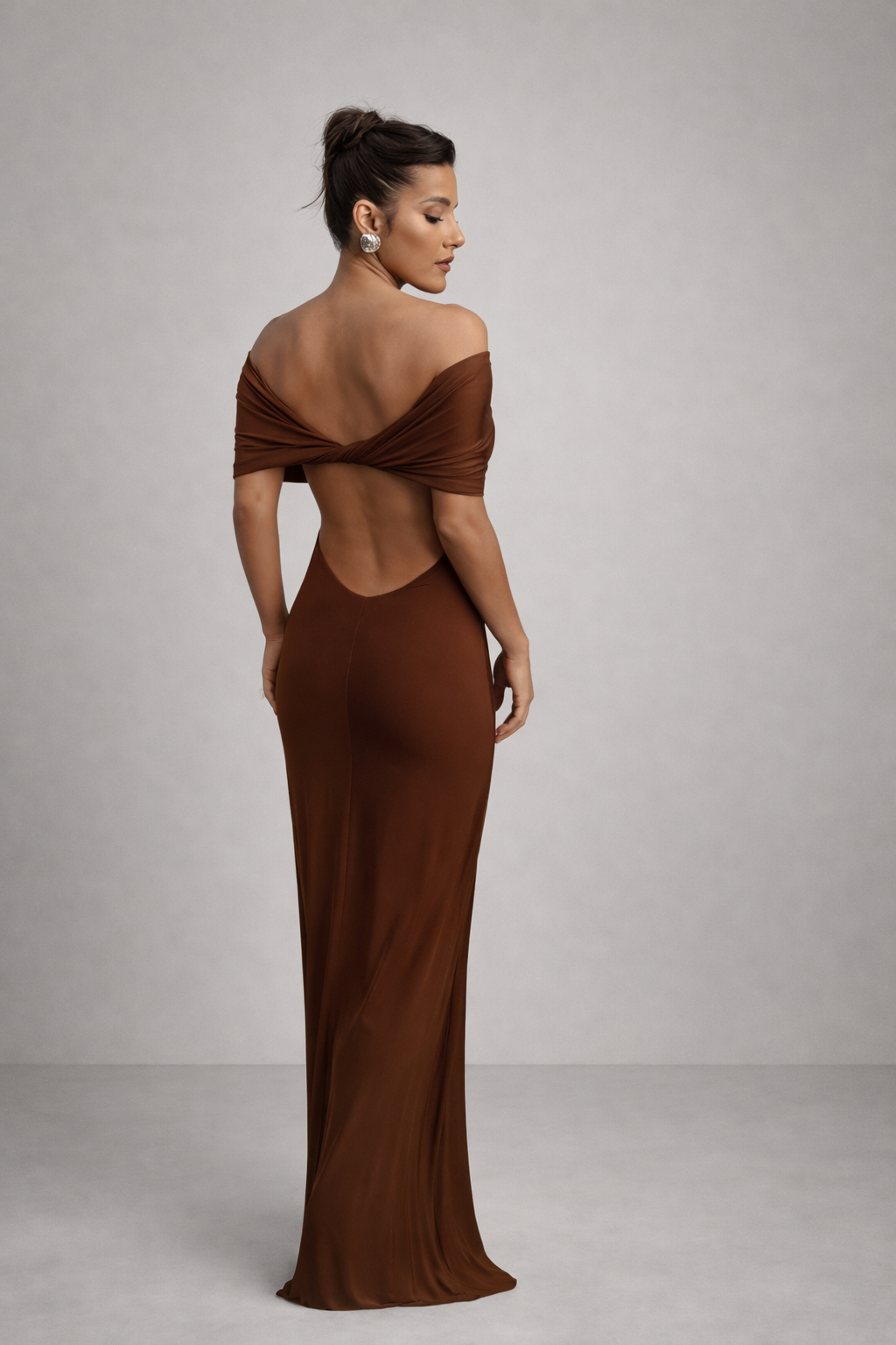 Woman wearing a brown evening gown with an open back against a gray background