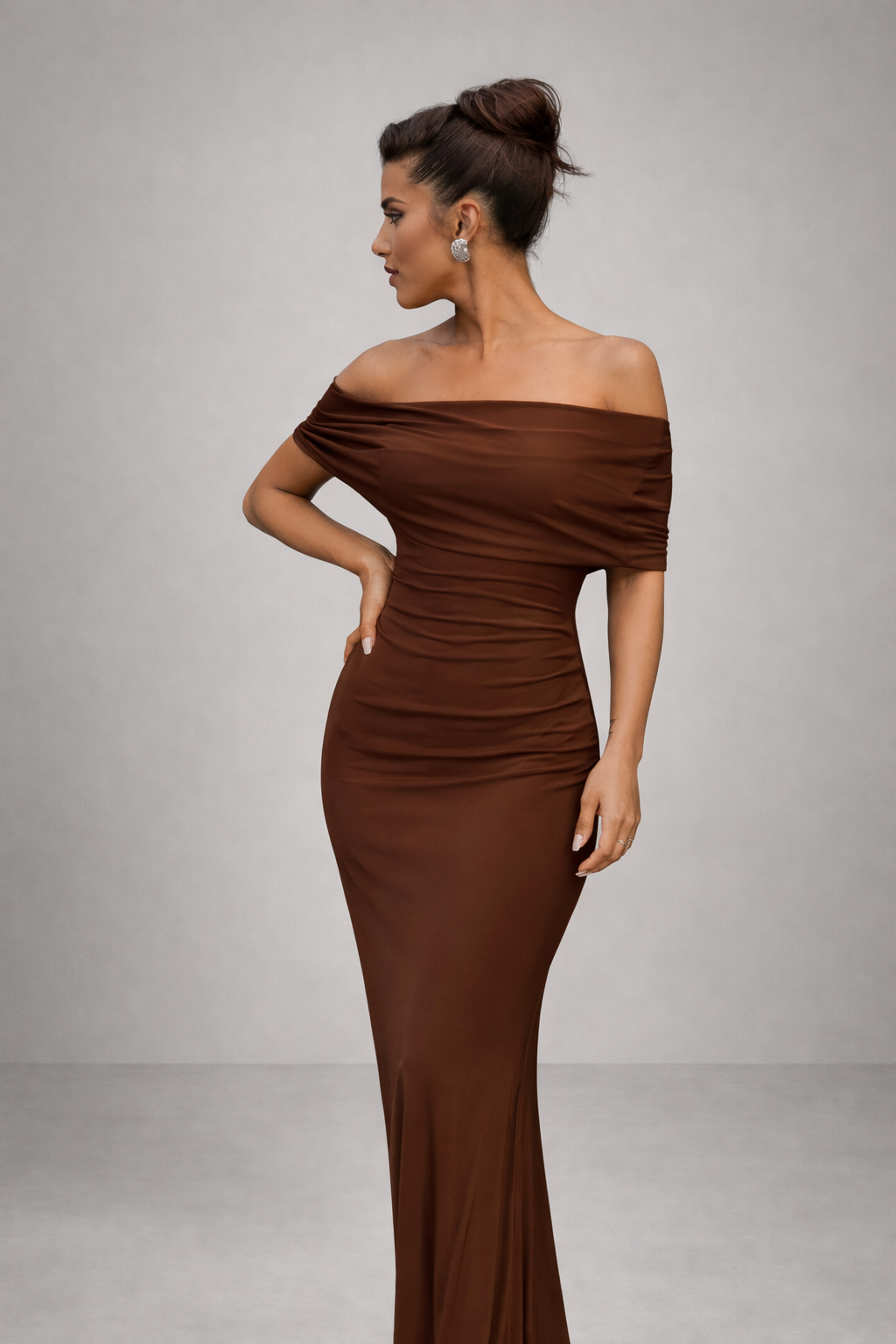 Woman wearing a brown off-shoulder gown against a gray background
