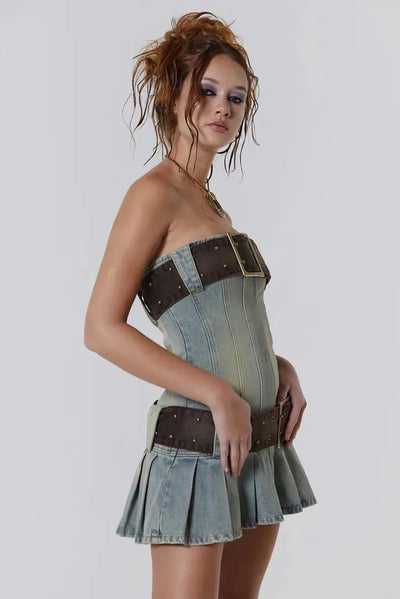 Woman wearing a denim dress with a brown belt on a plain background