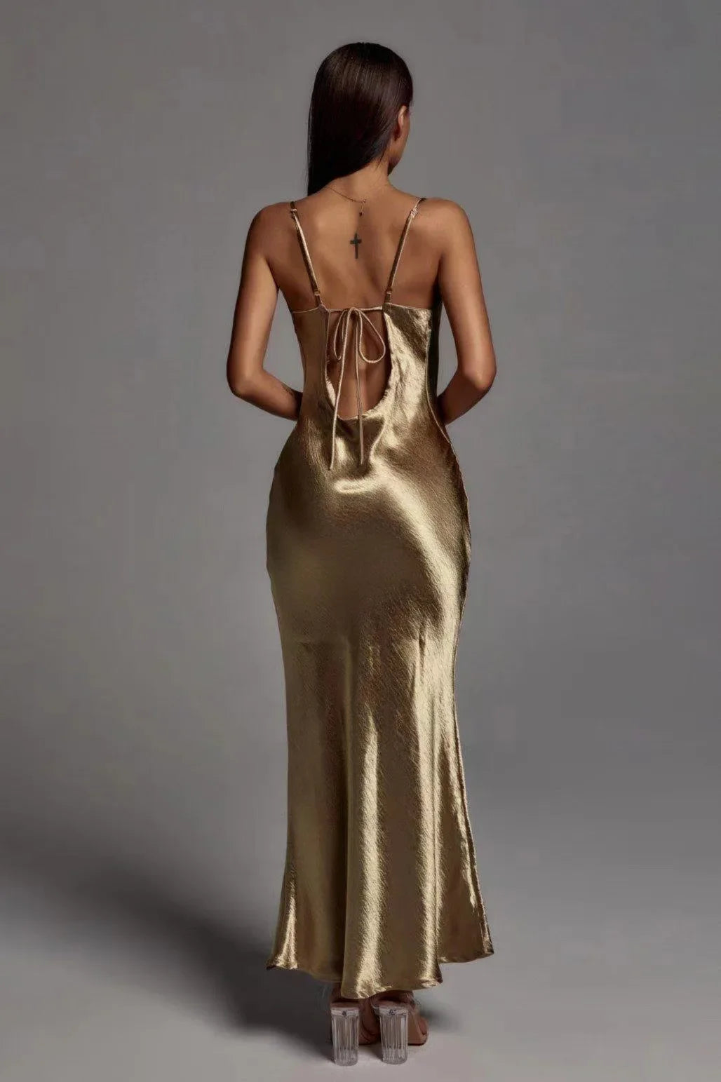 Woman wearing a gold satin slip dress against a gray background