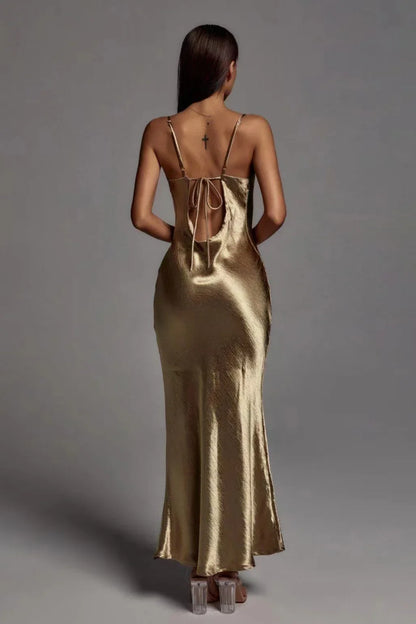 Woman wearing a gold satin slip dress against a gray background