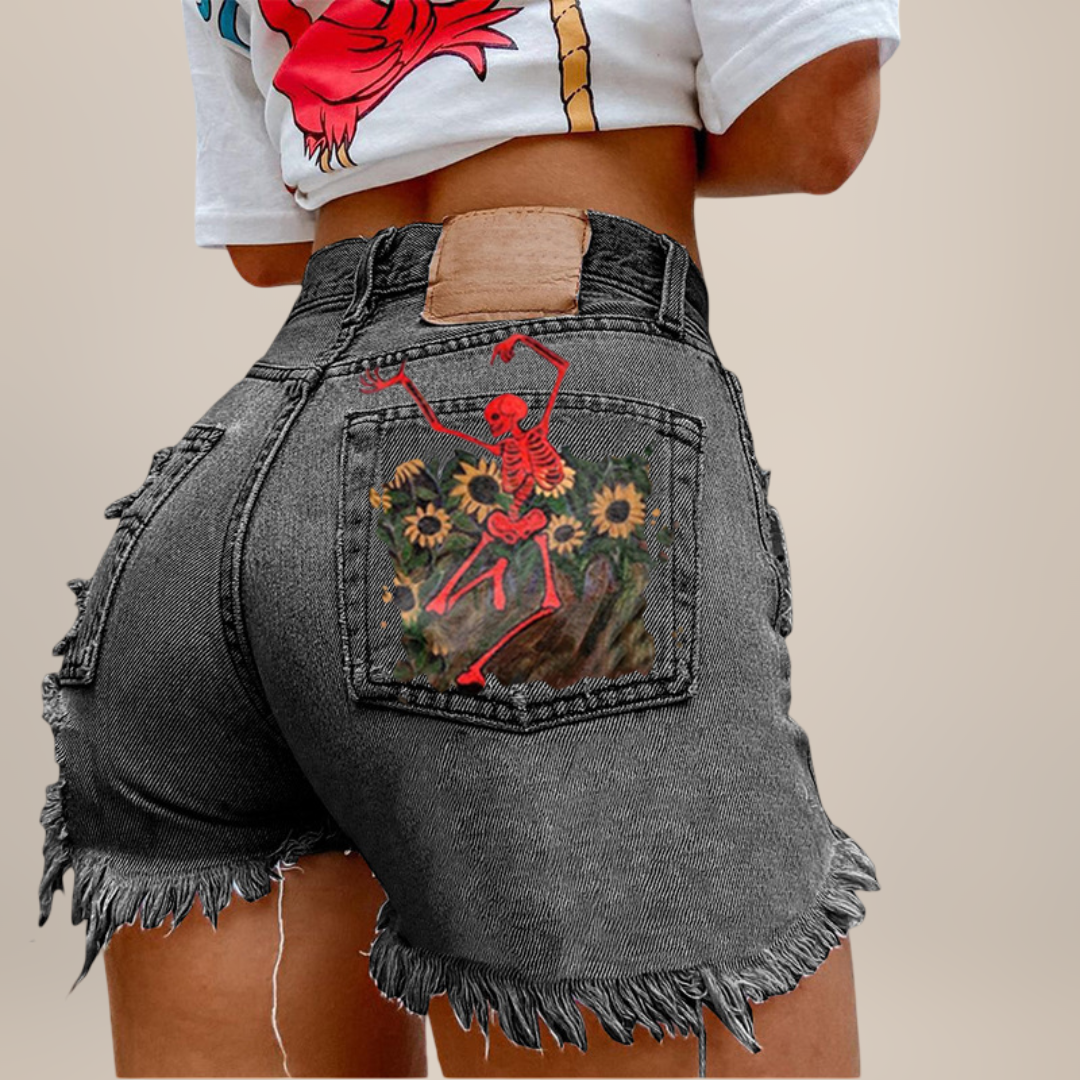 Person wearing gray denim shorts with a red skeleton design on the back pocket against a beige background