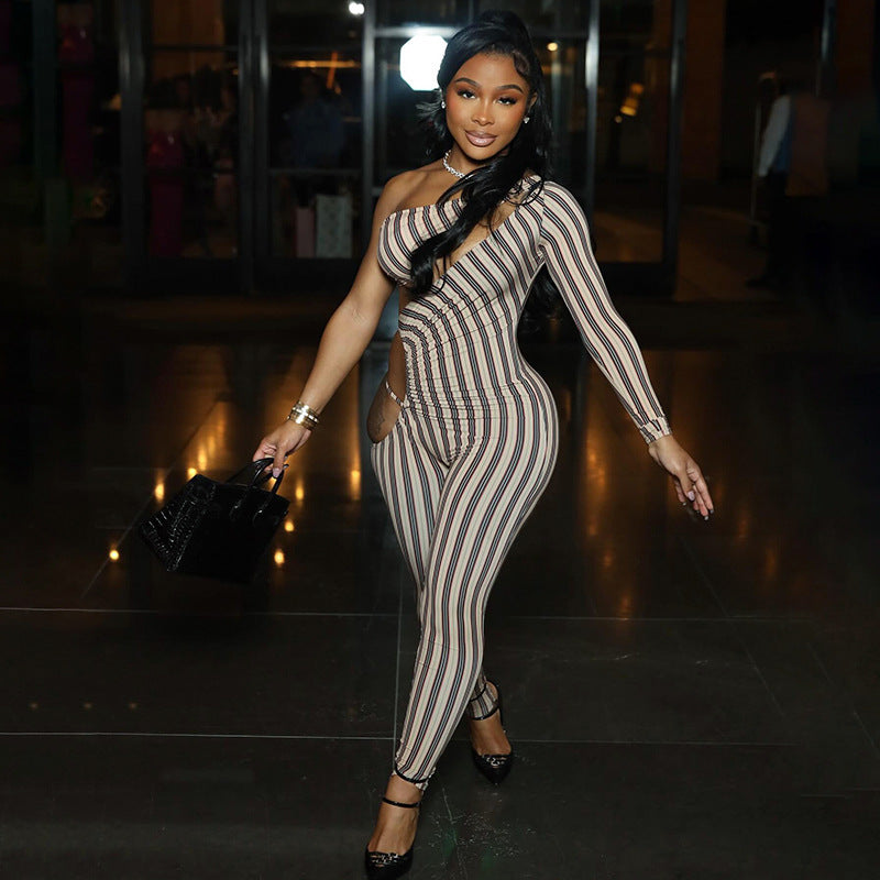 A woman wearing a striped slim-fit jumpsuit with hollow-out details. The jumpsuit is primarily monochrome with a bold striped pattern.