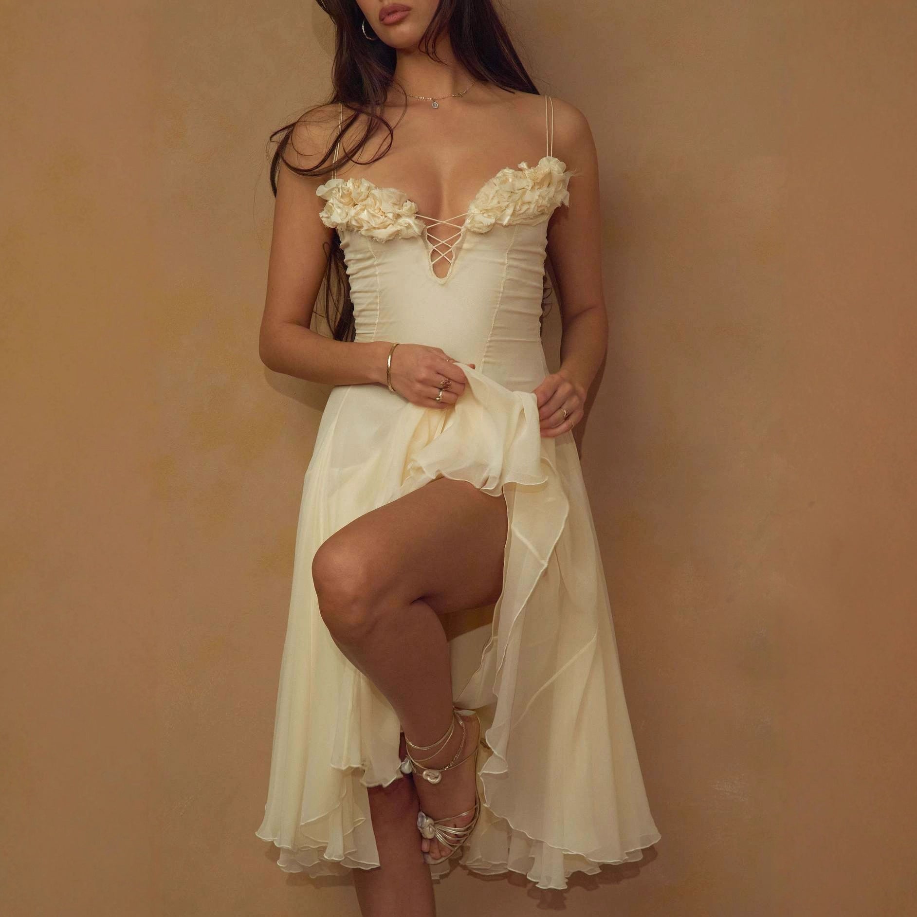 Woman wearing a white lace dress against a beige background