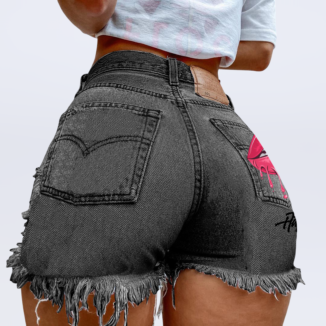 Person wearing black denim shorts with a pink design on a plain background