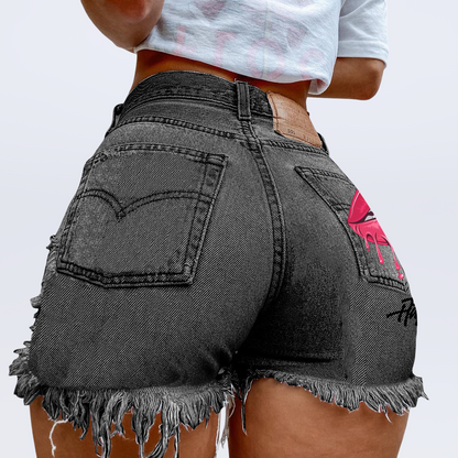 Person wearing black denim shorts with a pink design on a plain background