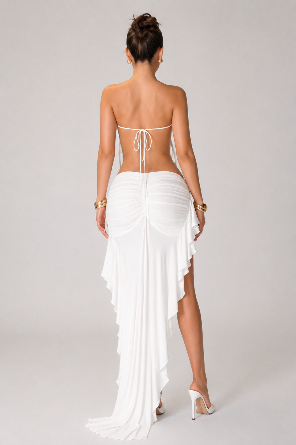 white halter maxi dress with an open back, draped neckline and asymmetrical ruffle hem